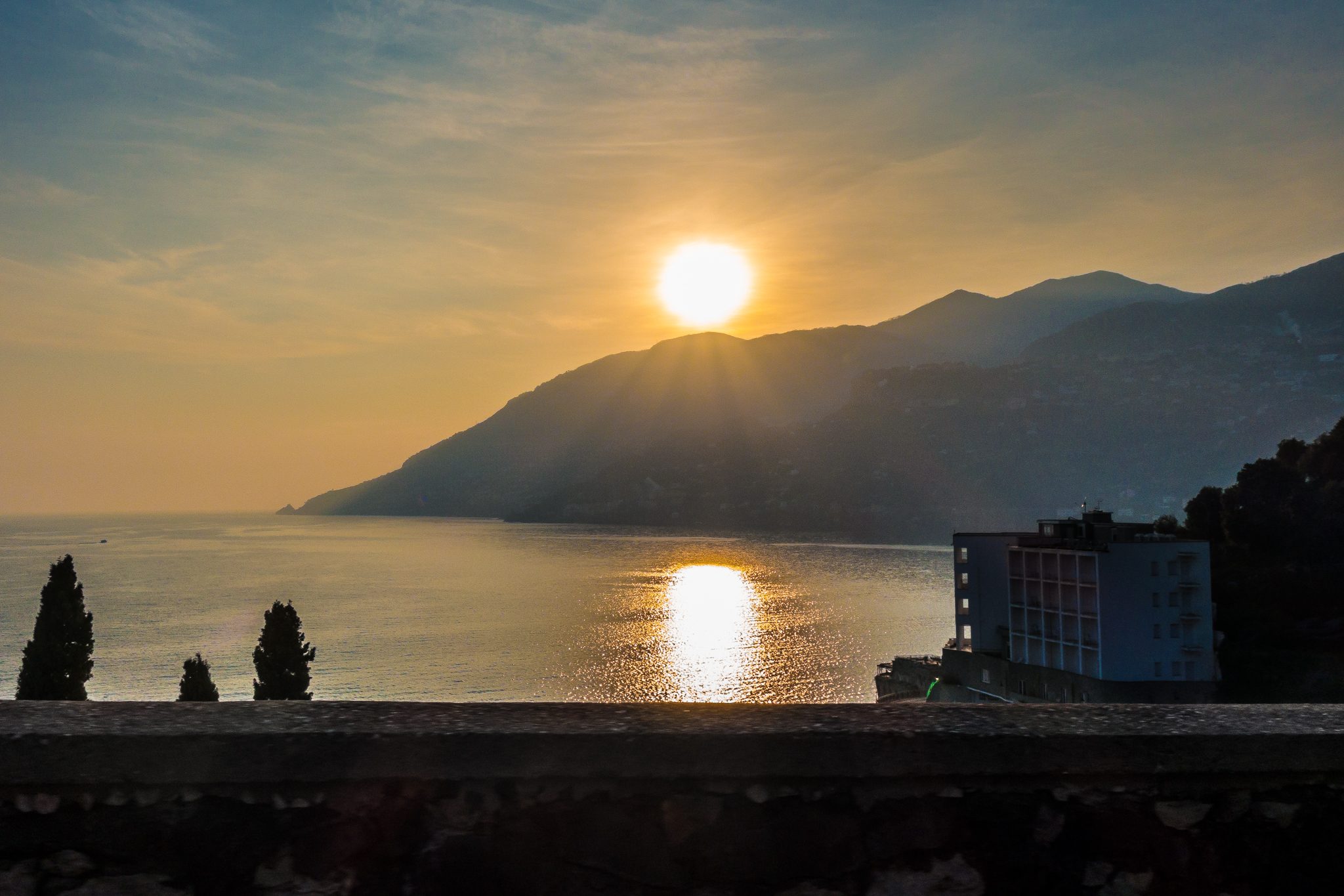 The sun setting over the mountains of the Amalfi Coast, reflected in the sea